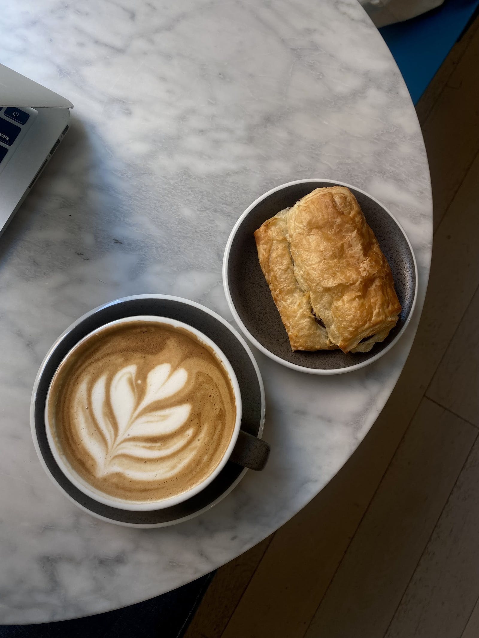 Coffee shop overhead shot of designed latte and chocolate croissant. 