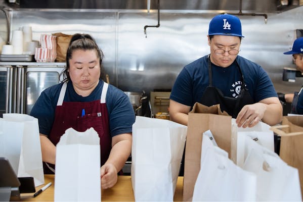 Image of two restaurant workers packing for delivery