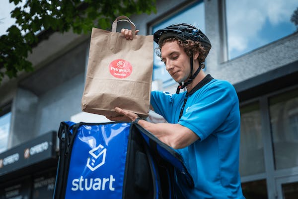 Image of a Stuart delivery partner placing a food package into the delivery bag